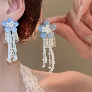 Detail of French tulle crystal flower tassel earrings with blue petals and white beads