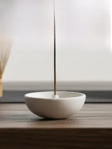 Macro detail of white ceramic tea bowl incense holder on a dark wooden zen tea table