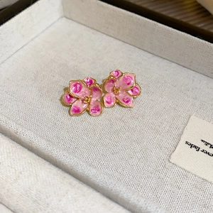 Detailed close-up of pink flower earrings with gold edges in a light jewelry box
