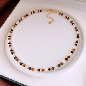 Détail des perles d'œil de tigre et pendentif cœur dans une boîte à bijoux blanche