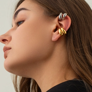 Detail of gold and silver rivet ear cuffs showing polished finish on a model's ear