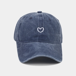 Detail of white heart embroidery on a vintage washed dark blue denim baseball cap