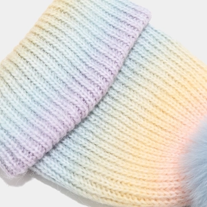 Détail du bonnet en maille arc-en-ciel avec pompon en fausse fourrure bleu clair