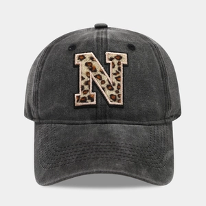 Close-up of washed black denim baseball cap with leopard print letter N embroidery detail