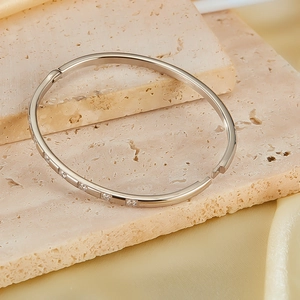 Close-up of a silver stainless steel bangle with square-cut cubic zirconia on stone base