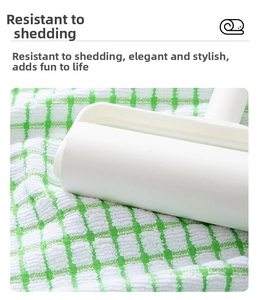 Detailed view of the white lint roller cleaning a green and white checkered tea towel