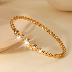Detail eines 18k Gold-Perlenarmbands mit 5 Zirkonia-Steinen auf einem Keramikteller