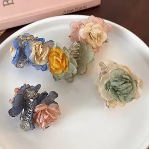 Set of five gradient camellia flower hair claws in soft pastel colors on a ceramic tray