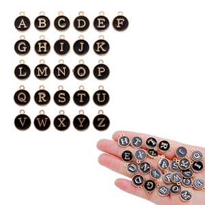 Hand holding round black enamel A-Z letter charms with gold finish for jewelry DIY