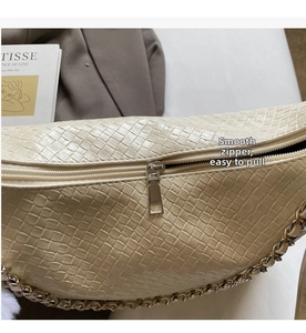 Detail of smooth metal zipper and woven texture on a beige shoulder bag with gold chain