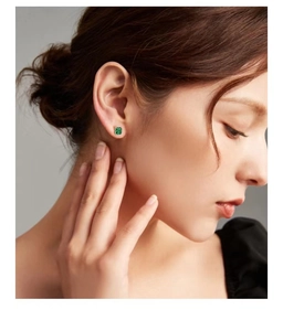 Close-up of a vintage square emerald earring on woman ear with gold texture frame
