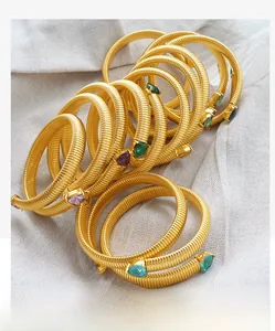 Detail of gold snake bone spring bracelets featuring colorful teardrop-shaped gemstones