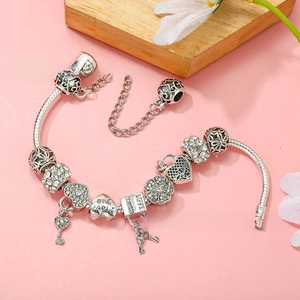 Close-up of silver charm bracelet with heart lock, key pendant and Love engravings