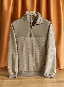 Dettaglio di un maglione lavorato beige con motivi a treccia e colletto con zip