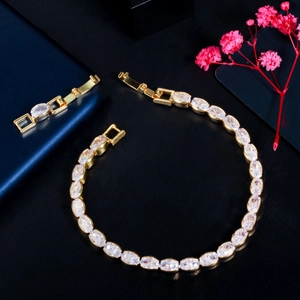 Detail of gold tennis bracelet with oval cubic zirconia stones on black background