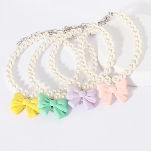 Detailed view of pearl pet necklaces with colorful macaron resin bow pendants
