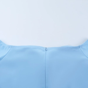 Dettaglio dell'abito azzurro che mostra le cuciture dello scollo a V e la cerniera