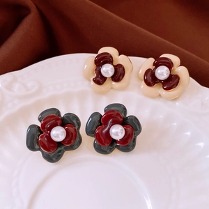 Close-up of double-layer flower stud earrings with pearls on a vintage ceramic plate