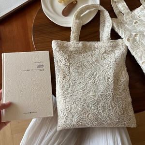 Vintage off-white lace embroidery tote bag on a rustic wooden table setting