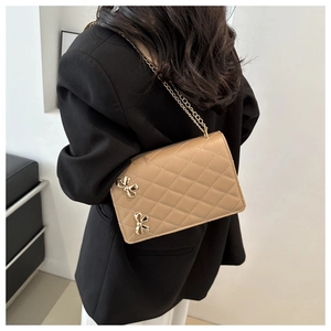 Detail view of khaki quilted crossbody bag featuring elegant gold butterfly ornaments