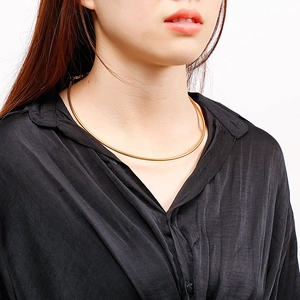 Detail of a thin gold snake chain necklace showing fine metallic texture on neck
