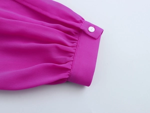 Dettaglio della manica in chiffon rosa con polsino a pieghe e bottone bianco sull'abito