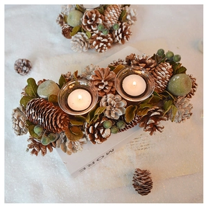 Detail of pine cone candle holder with glass tea light cups and winter festive greenery