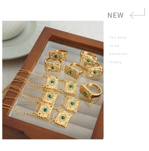 Close-up of gold evil eye jewelry set with green gemstones in a wooden display box