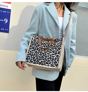 Detail of linen tote bag featuring leopard print, brown leather straps, and shoulder strap