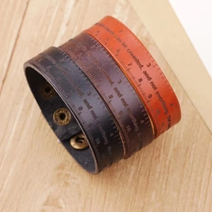 Three leather heartbeat bracelets in black and brown styles on wood surface