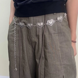 Vintage silver heart-shaped link waist chain with embossed patterns on dark trousers
