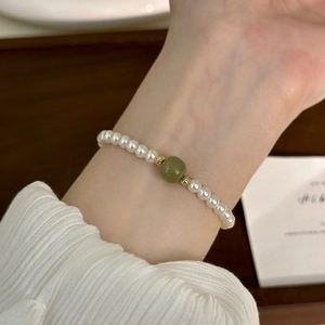 Elegant freshwater pearl bracelet with green bead and gold accents on a wrist