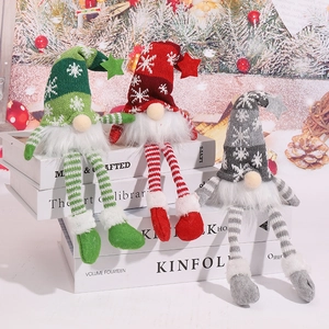 Tre gnomi di Natale in rosso verde e grigio con luci su un accogliente tavolo festivo