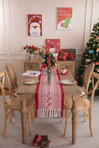 Detail of red Christmas table runner with white reindeer, snowflakes and tassel trim