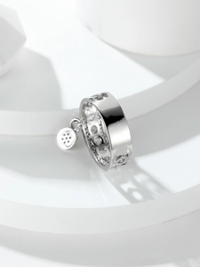 Detailed view of silver wide hollow ring with geometric patterns and round pendant