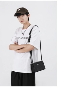 Detail of black faux crocodile leather box bag with CONE KNOWS logo and adjustable strap