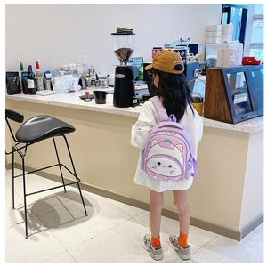 Girl wearing a light purple cartoon kitten backpack in a cafe setting, back side view