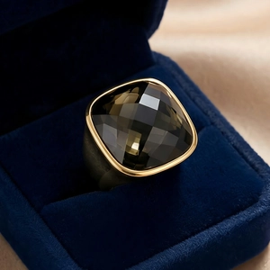Close-up of a cushion-cut brown crystal ring with a matte gold-finish metal band