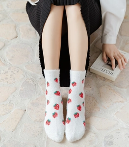 Detail of plush mink fleece mid-calf socks with strawberry print in a cozy home setting