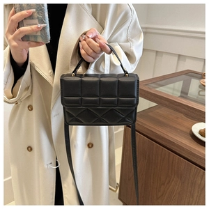 Detail of black quilted PU leather crossbody bag with gold hardware and top handle