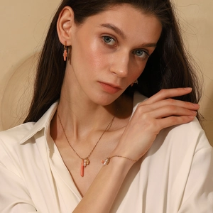 Elegant 18K gold plated jewelry set with peach bar pendants and pearls worn by a model
