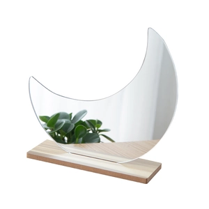 Irregular moon shaped acrylic mirror with a minimalist natural wood base stand