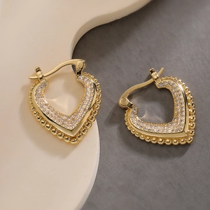 Elegante 18K vergoldete Herz-Creolen mit Zirkonia-Steinen auf einem beigen Schmuckständer