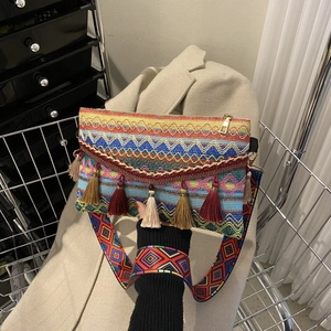 Detail of colorful woven shoulder bag with multi-color tassels and wide geometric strap