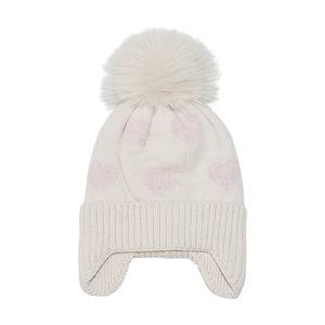 Details der Stricktextur von cremefarbener Babymütze mit rosa Herzen und Kunstfell-Bommel