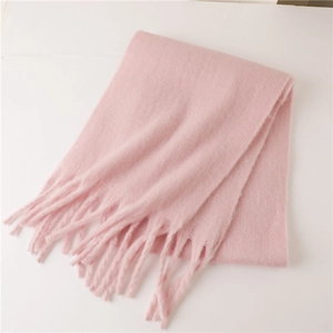 Gros plan sur la texture douce en mohair et les longues franges de cette écharpe rose