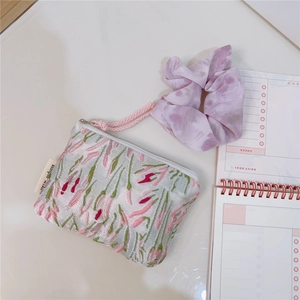 Detailed shot of pink floral embroidery pouch with purple tie-dye scrunchie and zipper