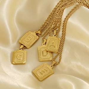 Cinq colliers 18K avec pendentifs lettres A-E et chaînes torsadées sur soie dorée