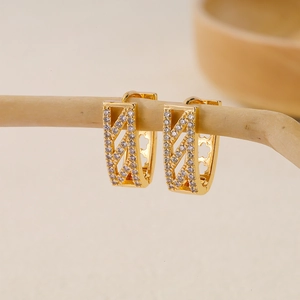 Close-up of geometric V-shaped gold earrings with paved white cubic zirconia crystals