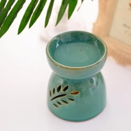 Ceramic essential oil burner with leaf-shaped hollow cutouts in a cozy home setting